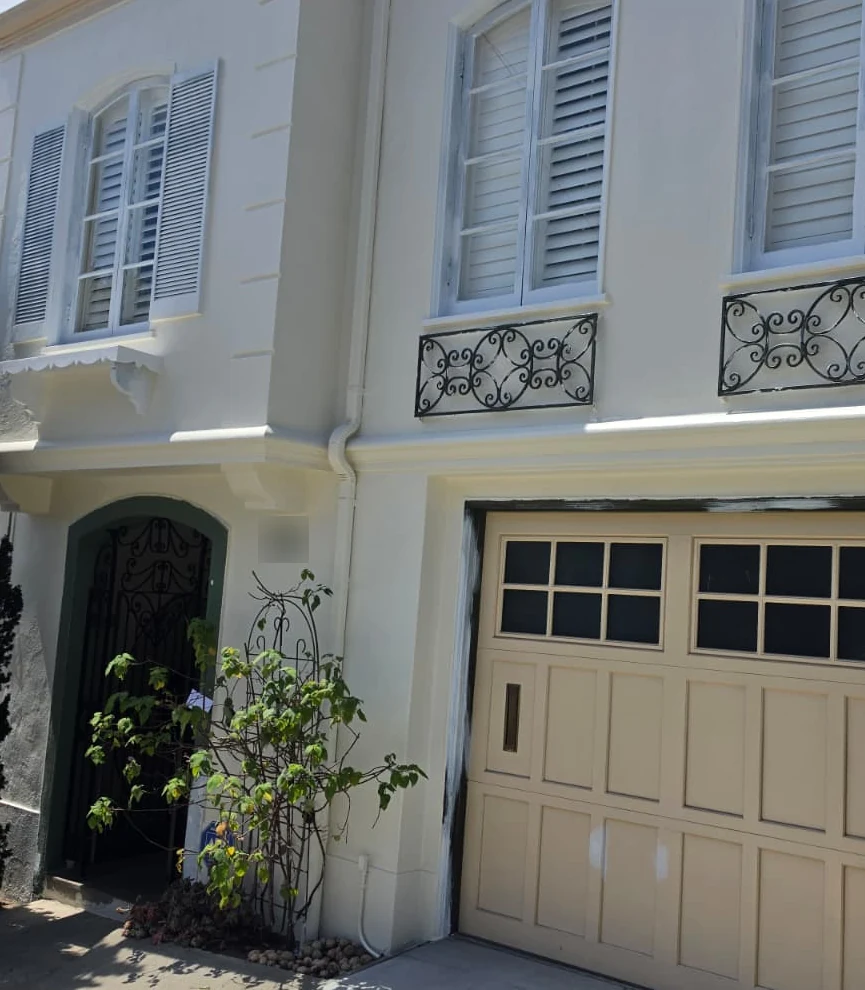 San Francisco house front before painting: beige garage door, primer patches and patched stucco, with no ladder